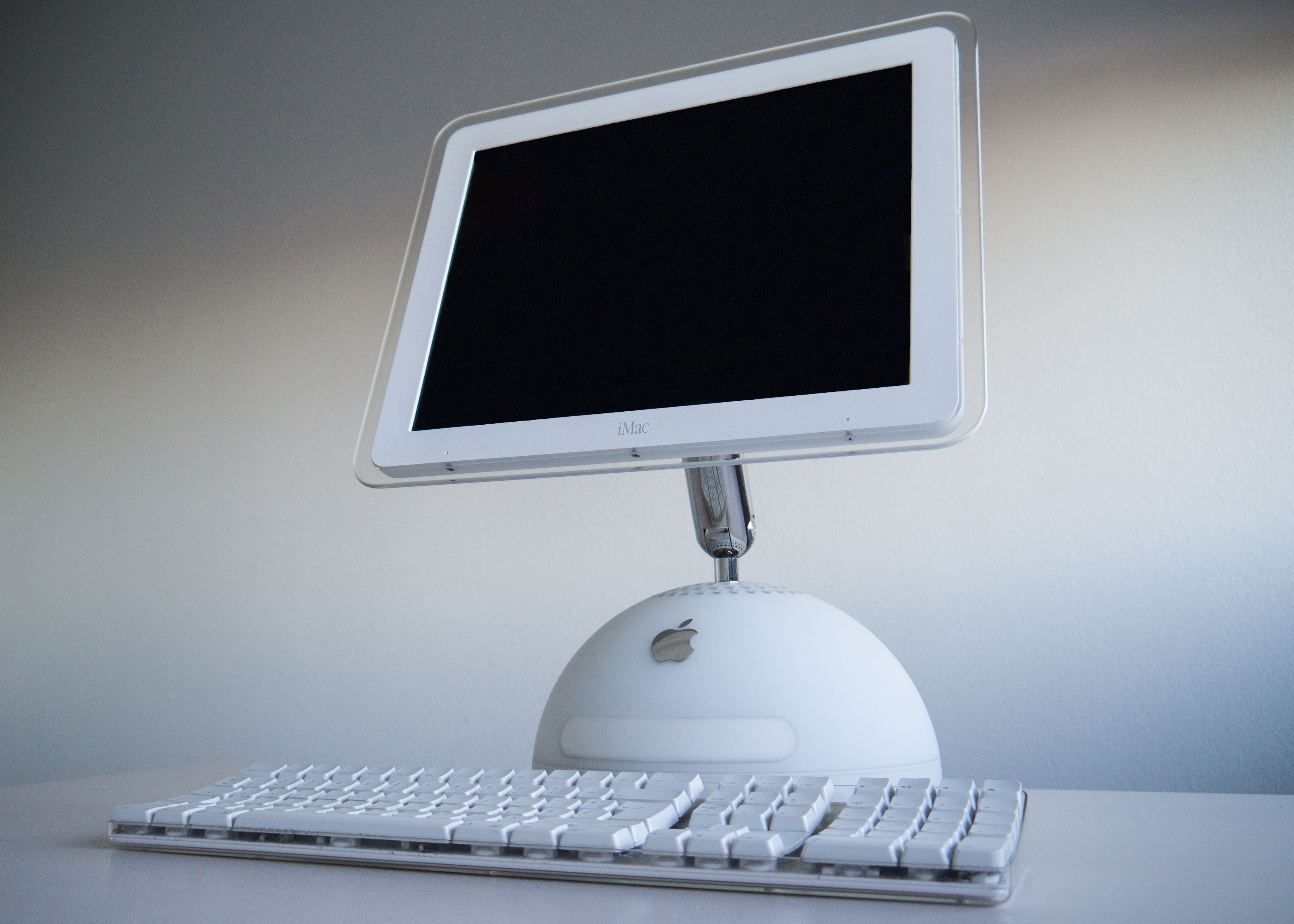 A white iMac G4 from 2002 with its flat screen on a chrome arm above a white dome base.